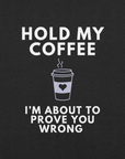 Close-up of black heather Milk Sandwich T-shirt with white bold text Hold My Coffee, I'm About to Prove You Wrong and a cute steaming coffee cup graphic.