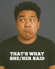 Man making a funny face, wearing a black “THAT’S WHAT SHE/HER SAID” t-shirt, looking off to the side.