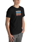 Angled front view of a man wearing a Milk Sandwich black t-shirt with a colorful distressed relax text design repeated vertically in white, blue, orange, and pink.