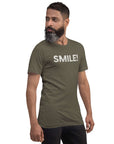 Side-facing man wearing army Milk Sandwich t-shirt with distressed white text that reads SMILE! on the chest, set against a white backdrop.