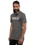 Man in a asphalt Milk Sandwich t-shirt featuring the word "SMILE!" in bold, distressed white letters, posing confidently with a slight turn against a white background.