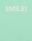 Close-up of heather mint Milk Sandwich t-shirt with the word "SMILE!" printed in bold, distressed white text across the chest.