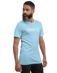 Side-facing man wearing ocean blue Milk Sandwich t-shirt with distressed white text that reads SMILE! on the chest, set against a white backdrop.