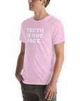 Man wearing a soft pink unisex Milk Sandwich T-shirt with the phrase "Truth is Not Fact" printed in bold white letters.