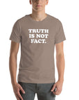 Unisex Milk Sandwich T-shirt in pebble featuring "TRUTH IS NOT FACT" graphic, perfect for comfortable and stylish everyday wear.