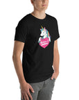 Man wearing a black t-shirt with a colorful unicorn graphic holding a pink heart that says “Believe in Edibles,” standing with hands in pockets, front and side view.