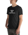 Man wearing a black t-shirt with white text ‘HIGH ON CREATIVITY’, standing sideways with one hand in pocket