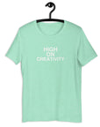Mint t-shirt on a hanger with the phrase “HIGH ON CREATIVITY” printed in white, centered on the chest.
