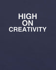 Close-up of navy t-shirt fabric with the phrase “HIGH ON CREATIVITY” printed in bold white uppercase letters in three lines.