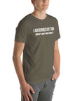 Man wearing army“I ABSORBED MY TWIN (What’s your super power?)” t-shirt, standing angled to the side with hands in pockets.