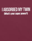 Close-up of maroon t-shirt with white text “I ABSORBED MY TWIN (What’s your super power?)” printed on the front.
