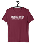 Maroon t-shirt hanging on a hanger with white text “I ABSORBED MY TWIN (What’s your super power?)” on the front.