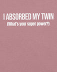 Close-up of orchid t-shirt with white text “I ABSORBED MY TWIN (What’s your super power?)” printed on the front.