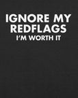 Close-up of black t-shirt with bold white text “IGNORE MY RED FLAGS I’M WORTH IT” printed on the front.