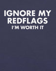Close-up of navy t-shirt with bold white text “IGNORE MY RED FLAGS I’M WORTH IT” printed on the front.