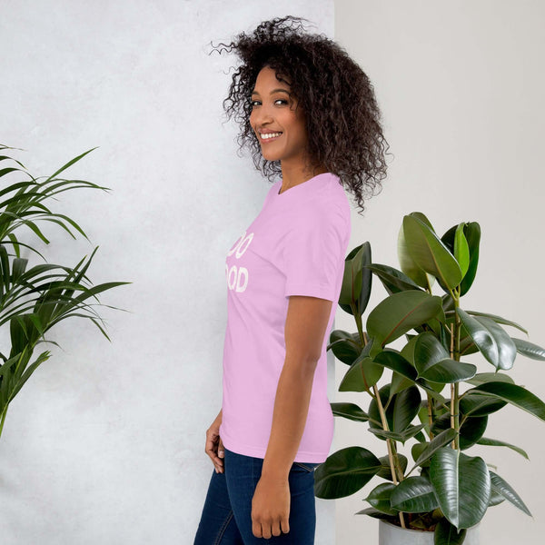 Side view of smiling woman wearing lilac Milk Sandwich T-shirt with DO GOOD slogan, standing near indoor plants, minimalist inspirational tee.