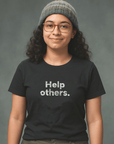 Smiling woman in glasses and knit beanie wearing black Milk Sandwich T-shirt with distressed white text that reads Help others. minimalist graphic tee.