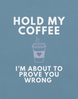 Close-up of steel blue Milk Sandwich T-shirt with white bold text Hold My Coffee, I'm About to Prove You Wrong and a cute steaming coffee cup graphic.