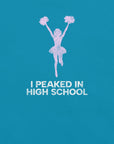 Close-up of aqua Milk Sandwich T-shirt with distressed pink cheerleader graphic and white text that reads I Peaked in High School, sarcastic retro tee.