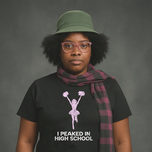 Serious woman in hat and scarf wearing black Milk Sandwich T-shirt with faded pink cheerleader graphic and text I Peaked in High School, ironic retro tee.
