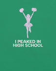 Close-up of green Milk Sandwich T-shirt with distressed pink cheerleader graphic and white text that reads I Peaked in High School, sarcastic retro tee.
