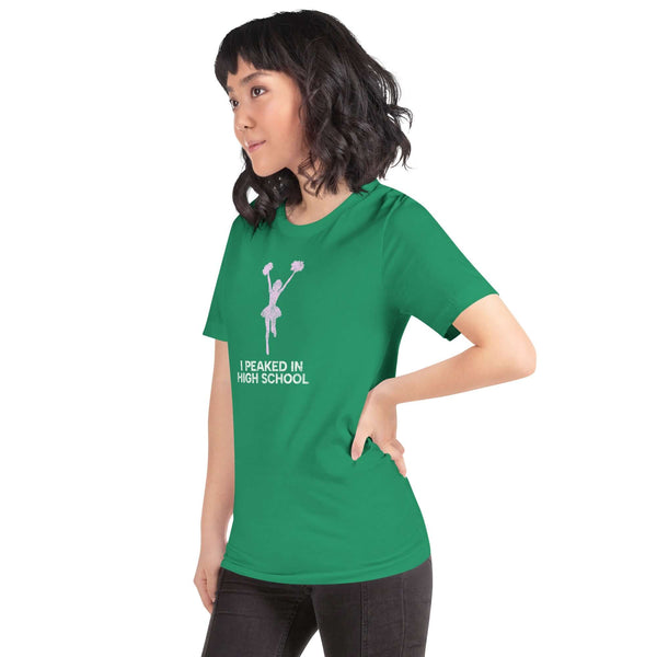 Model wearing a green unisex Milk Sandwich T-shirt that says "I Peaked in High School," showcasing its comfortable fit and fun design.