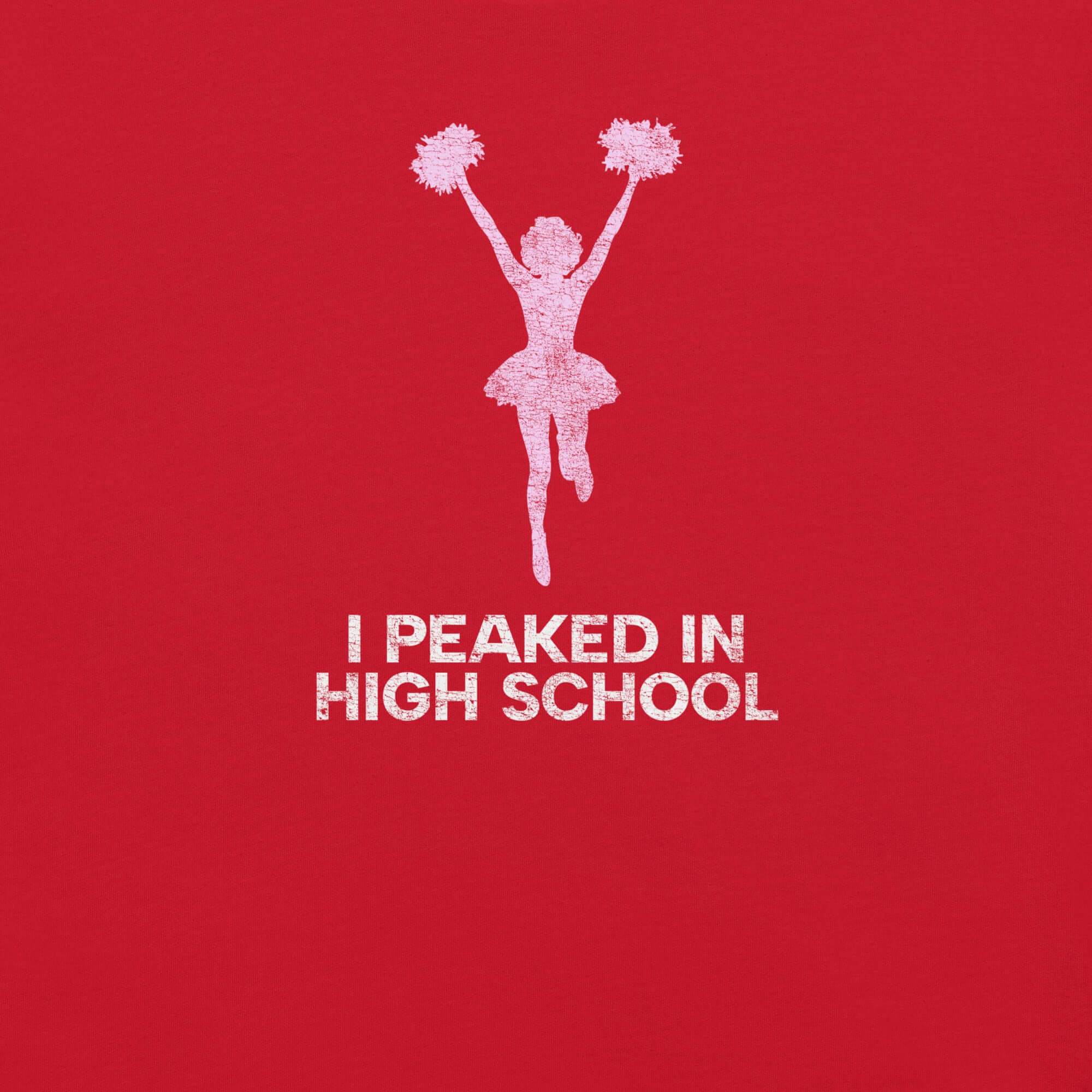 Close-up of red Milk Sandwich T-shirt with distressed pink cheerleader graphic and white text that reads I Peaked in High School,  sarcastic retro tee.