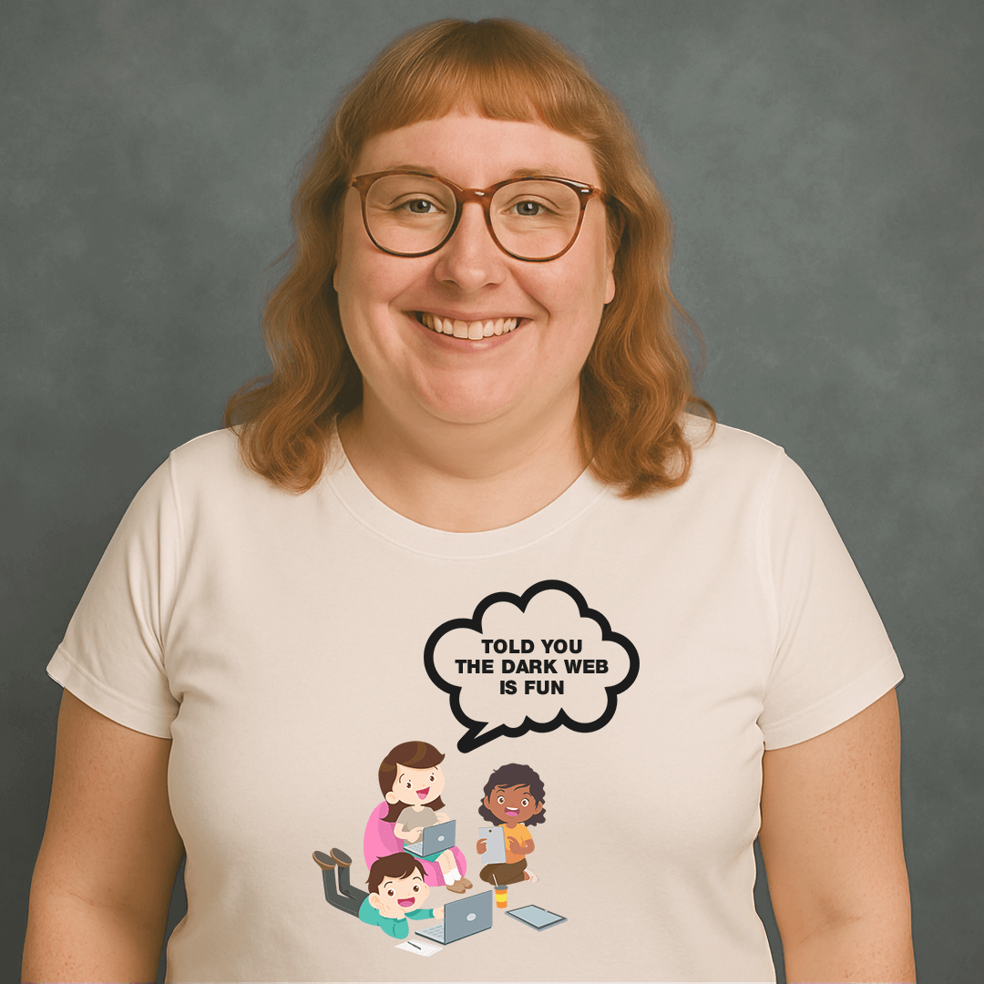 Smiling woman with glasses wearing a white t-shirt that says “TOLD YOU THE DARK WEB IS FUN” with cartoon kids on laptops.