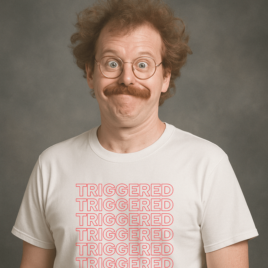 Man with glasses and mustache wearing a white “TRIGGERED” t-shirt, looking surprised and goofy in a vintage studio photo.
