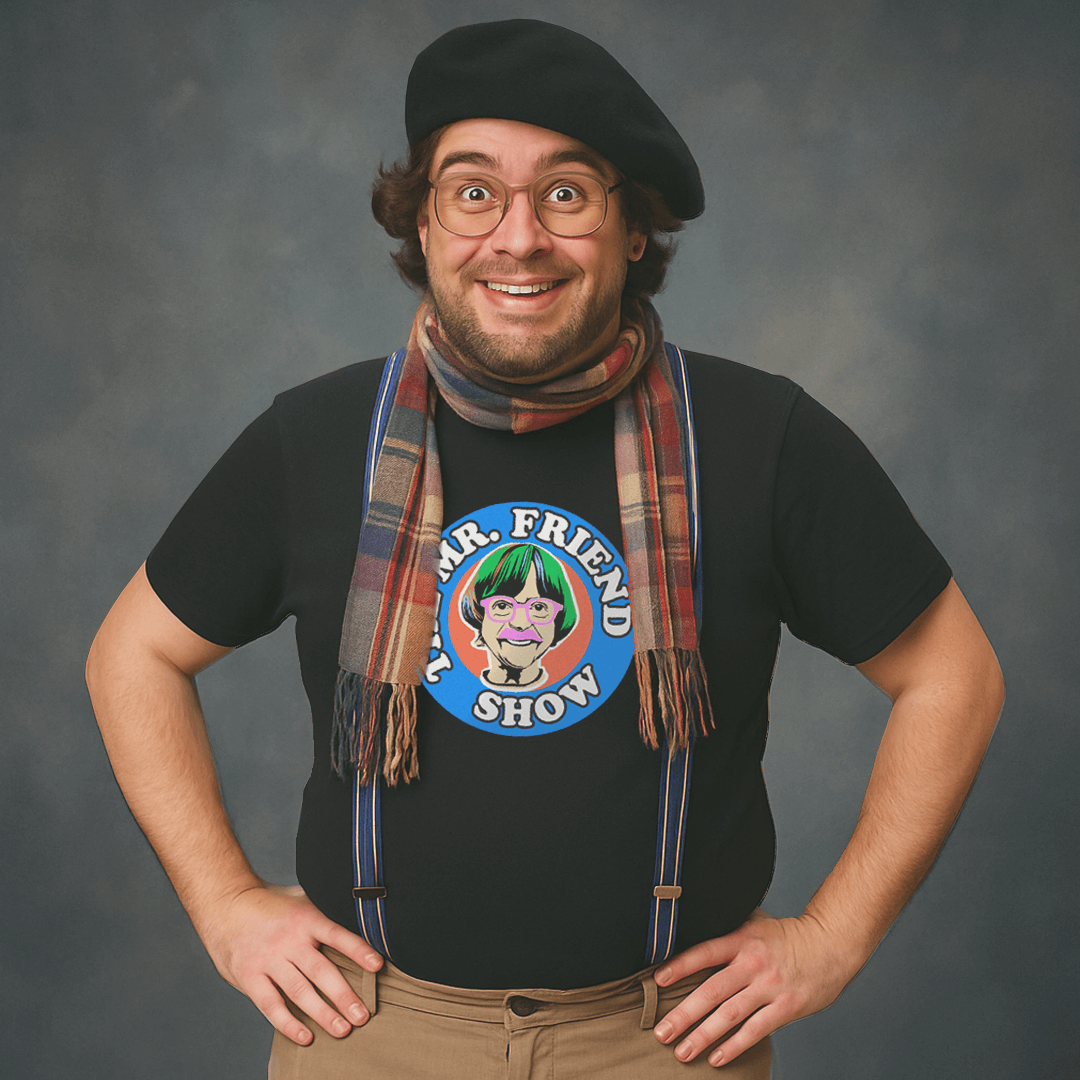 Smiling person wearing glasses, a beret, scarf, and suspenders with a black t-shirt featuring a colorful cartoon graphic of a character with green hair and the text “Mr. Friend Show.”