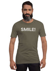 Man wearing a army Milk Sandwich t-shirt with the word "SMILE!" in bold, distressed white lettering across the chest, standing confidently against a plain background.