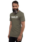 Man in a army Milk Sandwich t-shirt featuring the word "SMILE!" in bold, distressed white letters, posing confidently with a slight turn against a white background.