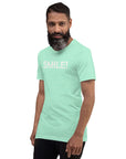 Man in a heather mint Milk Sandwich t-shirt featuring the word "SMILE!" in bold, distressed white letters, posing confidently with a slight turn against a white background.