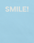 Close-up of ocean blue Milk Sandwich t-shirt with the word "SMILE!" printed in bold, distressed white text across the chest.