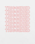 Close-up of white t-shirt with repeated red “TRIGGERED” text stacked in a bold outline font.