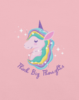 Close-up of a pink Milk Sandwich t-shirt with a pastel unicorn illustration and the phrase Think Big Thoughts in purple script, surrounded by sparkles.