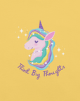 Close-up of a yelow Milk Sandwich t-shirt with a pastel unicorn illustration and the phrase Think Big Thoughts in purple script, surrounded by sparkles.