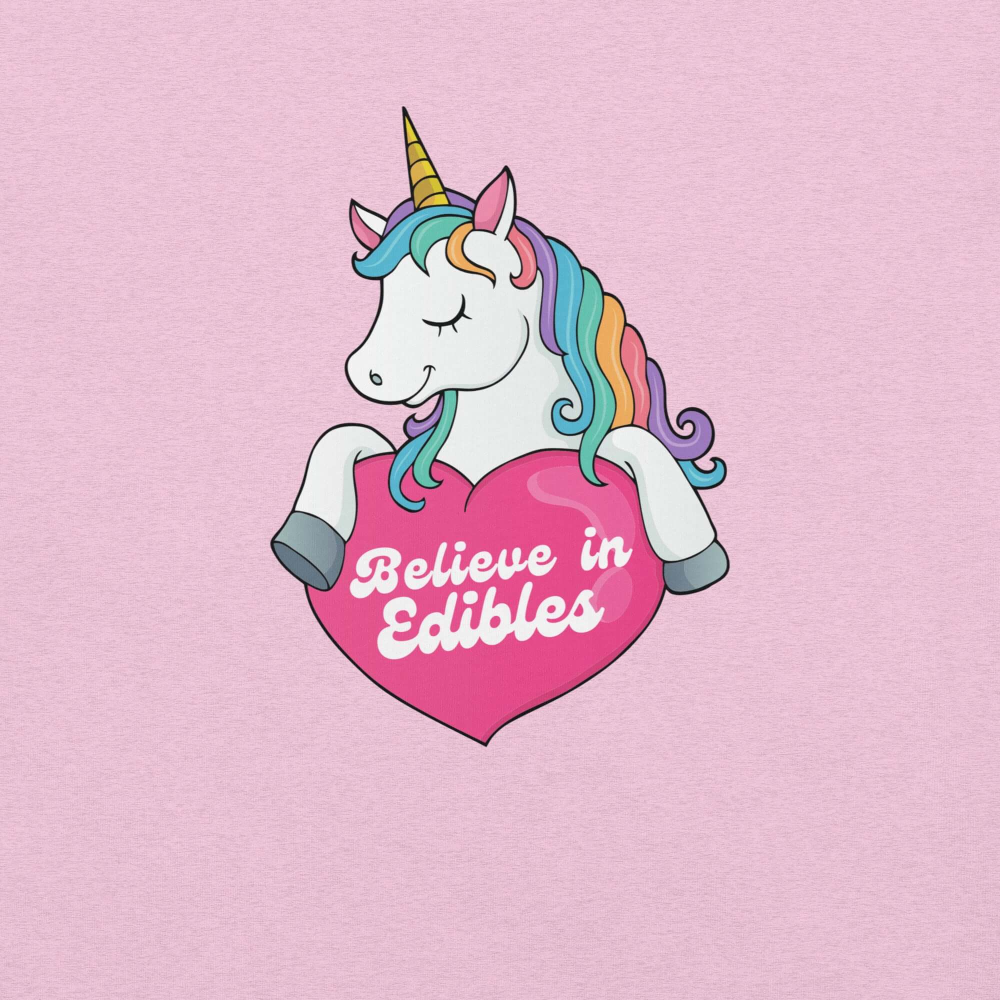 Close-up of a colorful unicorn graphic holding a pink heart with the text “Believe in Edibles” on a lilac fabric background.