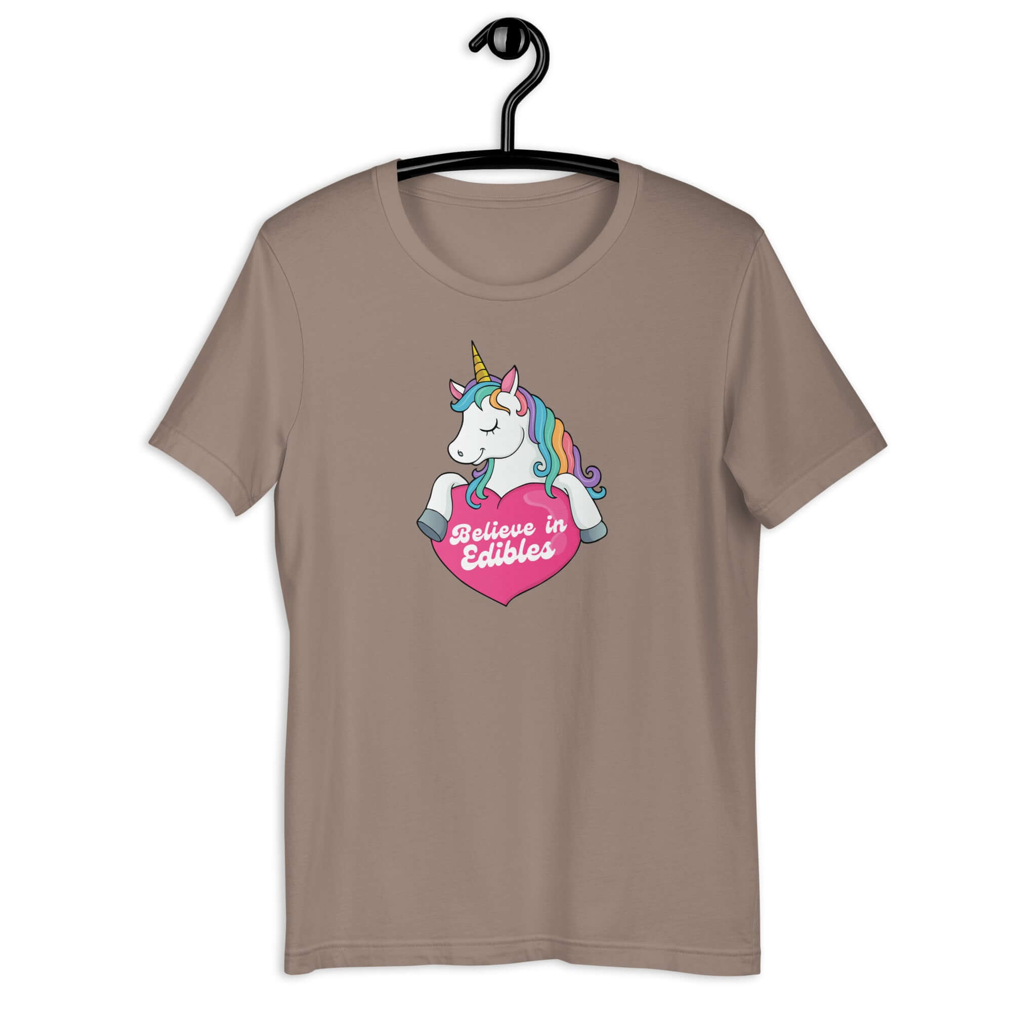 Pebble t-shirt on a hanger with a colorful unicorn graphic above a pink heart that says “Believe in Edibles.”