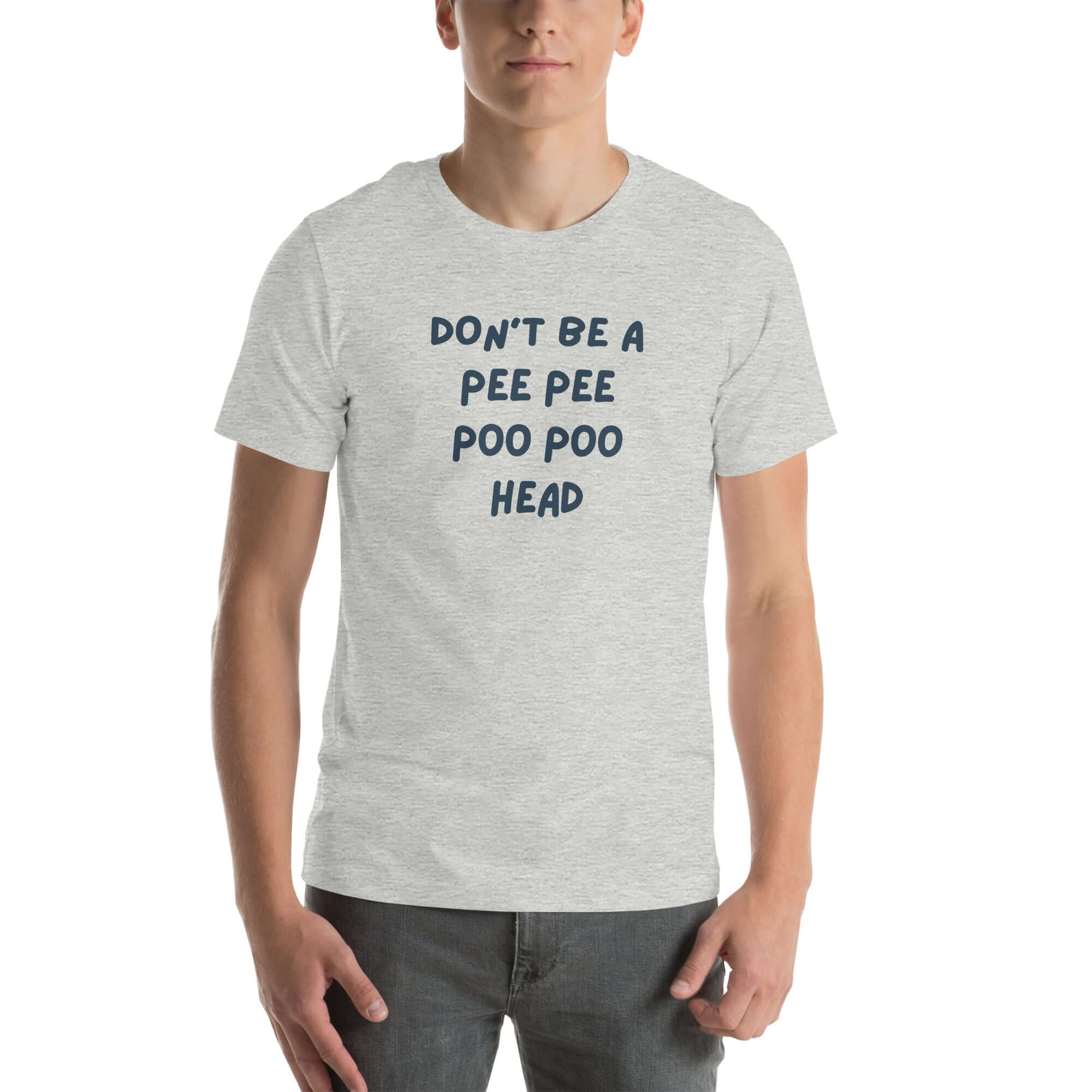 Man wearing light grey “DON’T BE A PEE PEE POO POO HEAD” t-shirt, standing casually with hands by pockets.