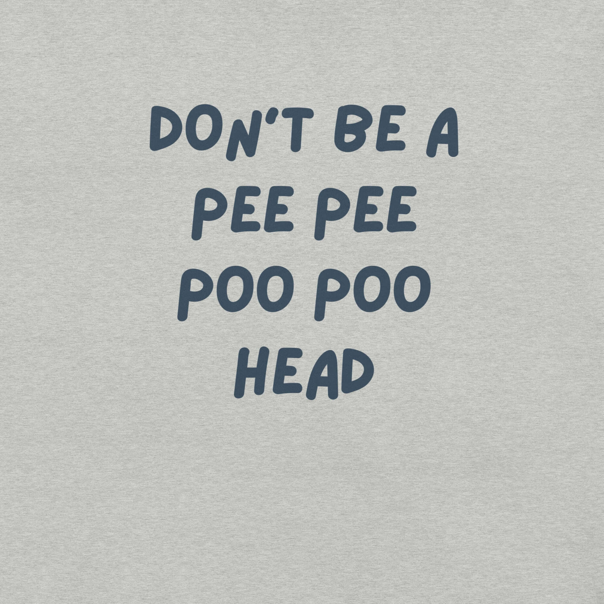 Man wearing light grey “DON’T BE A PEE PEE POO POO HEAD” t-shirt, standing casually with hands by pockets.