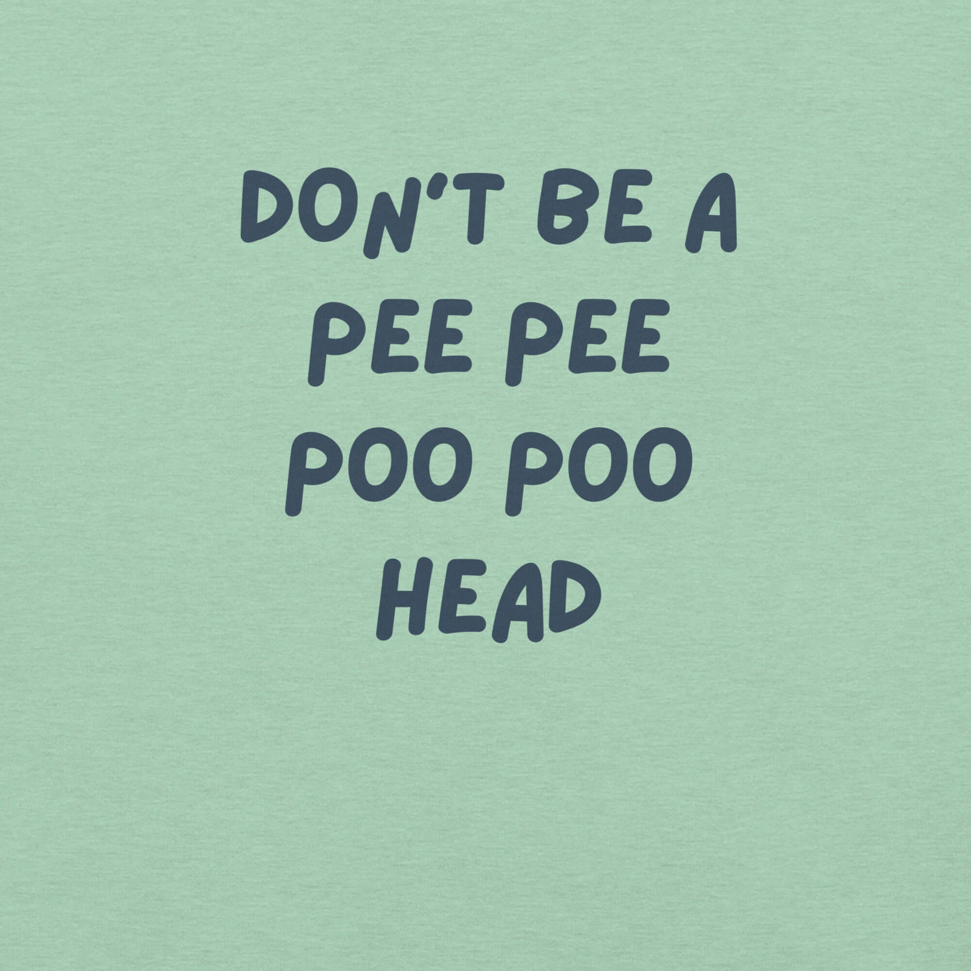 Man wearing mint “DON’T BE A PEE PEE POO POO HEAD” t-shirt, standing casually with hands by pockets.