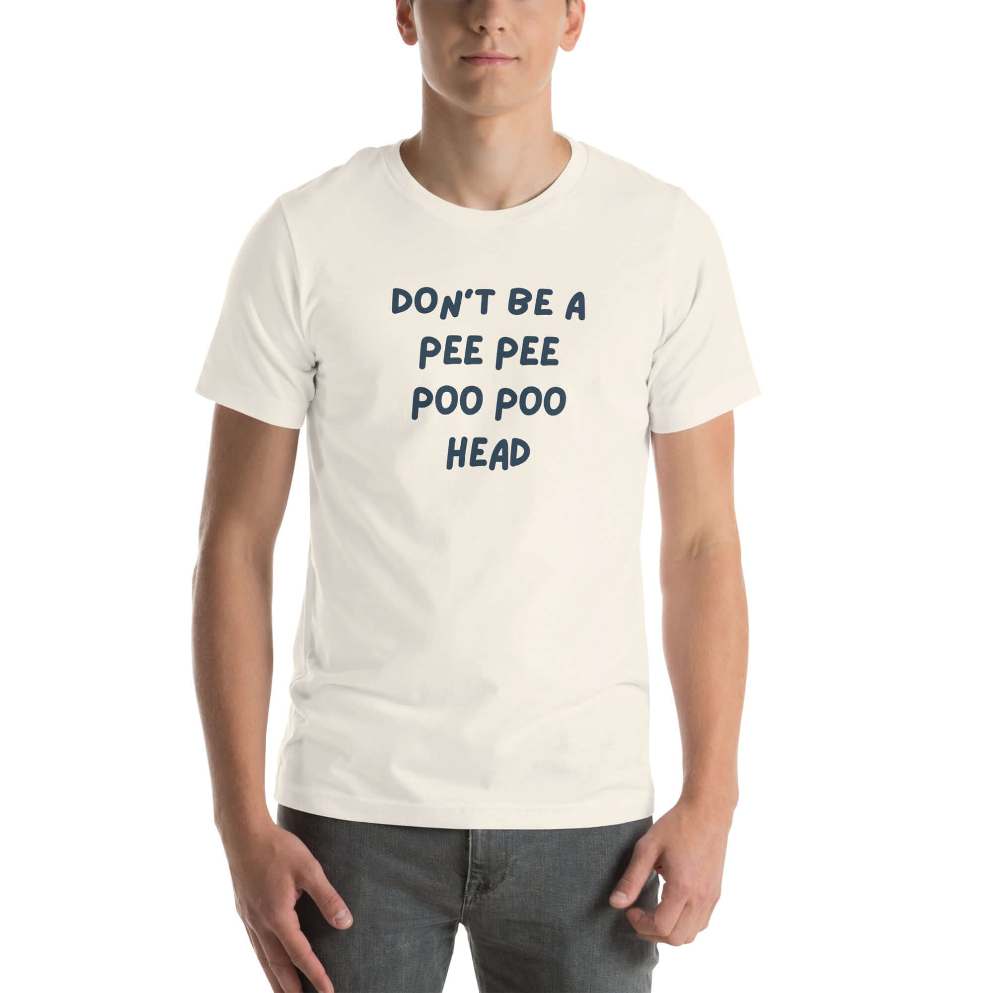 Man wearing white “DON’T BE A PEE PEE POO POO HEAD” t-shirt, standing casually with hands by pockets.