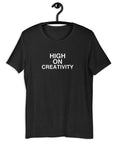 Black t-shirt on a hanger with the phrase “HIGH ON CREATIVITY” printed in white, centered on the chest.