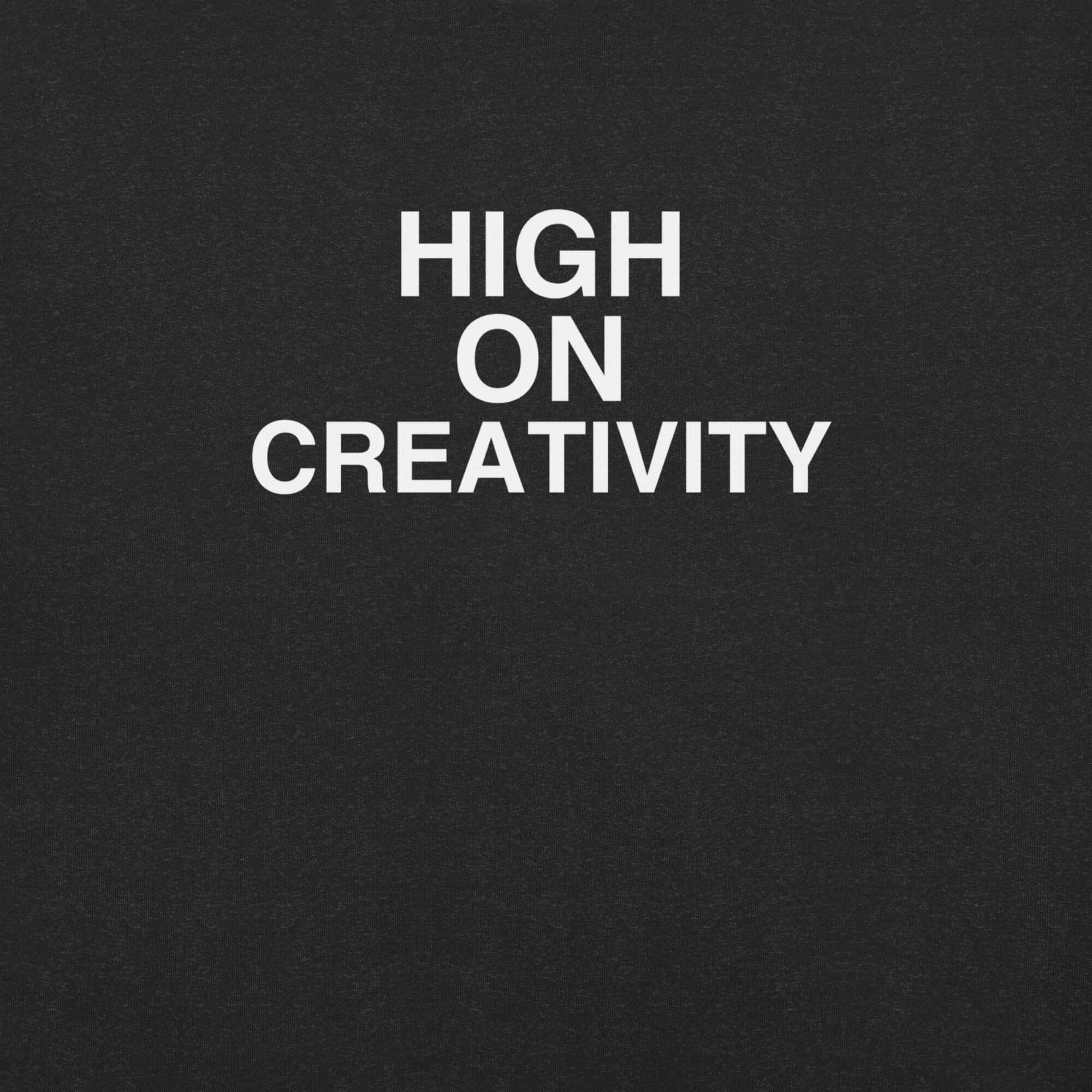 Close-up of black t-shirt fabric with the phrase “HIGH ON CREATIVITY” printed in bold white uppercase letters in three lines.
