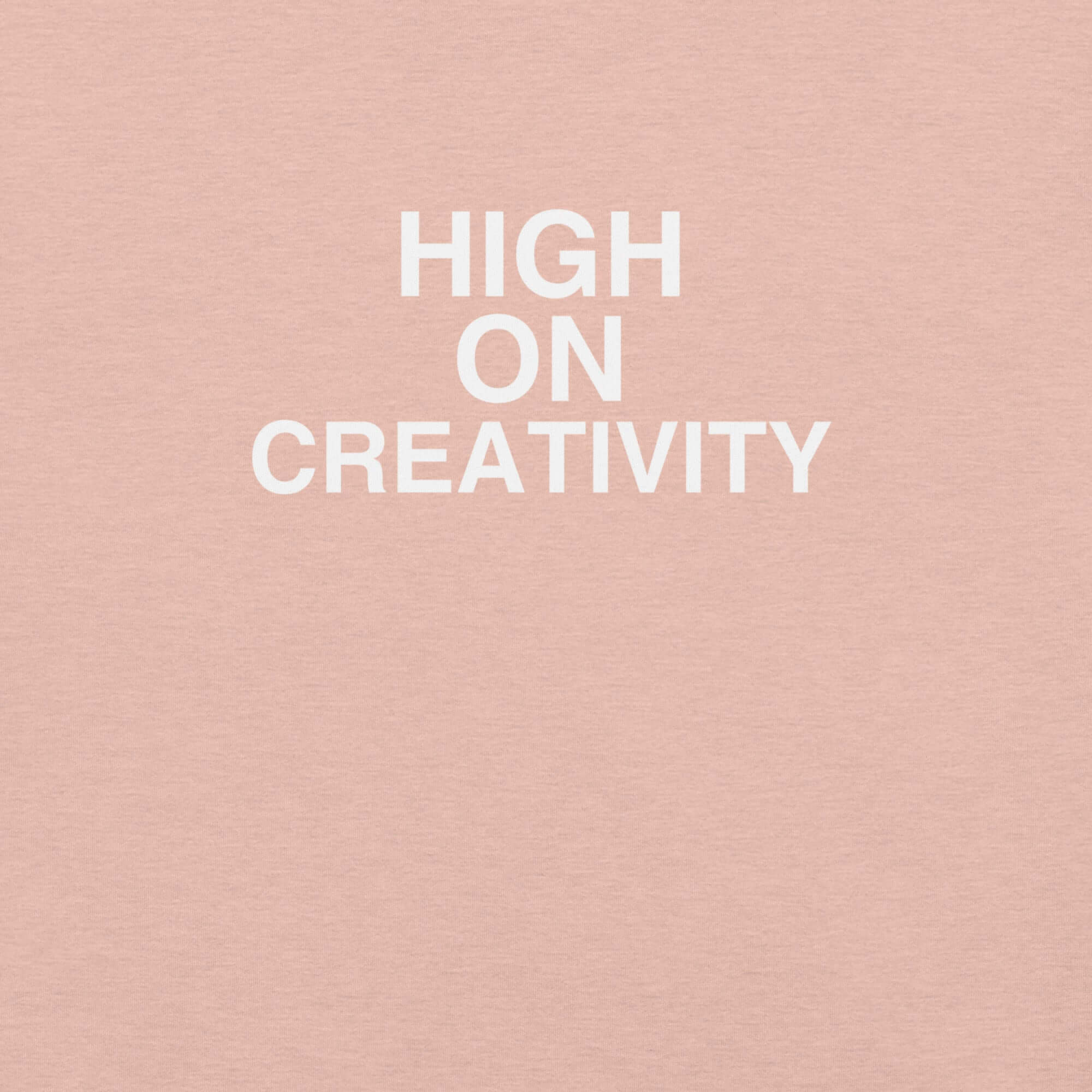 Close-up of peach t-shirt fabric with the phrase “HIGH ON CREATIVITY” printed in bold white uppercase letters in three lines.