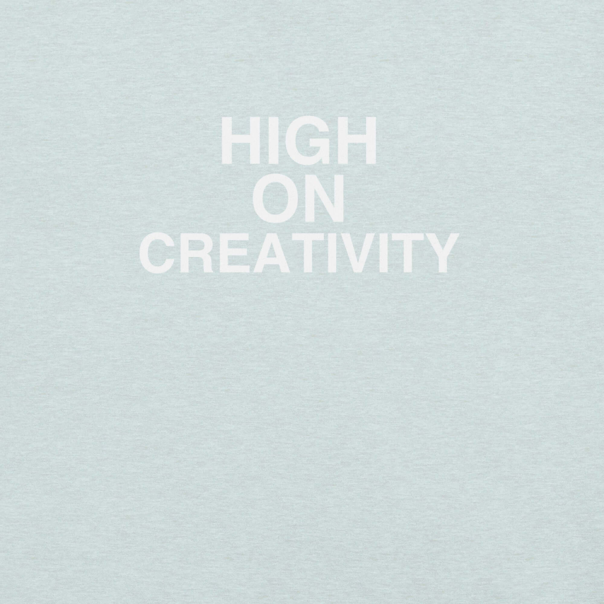 Close-up of ice blue t-shirt fabric with the phrase “HIGH ON CREATIVITY” printed in bold white uppercase letters in three lines.