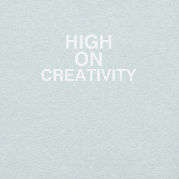 Close-up of ice blue t-shirt fabric with the phrase “HIGH ON CREATIVITY” printed in bold white uppercase letters in three lines.