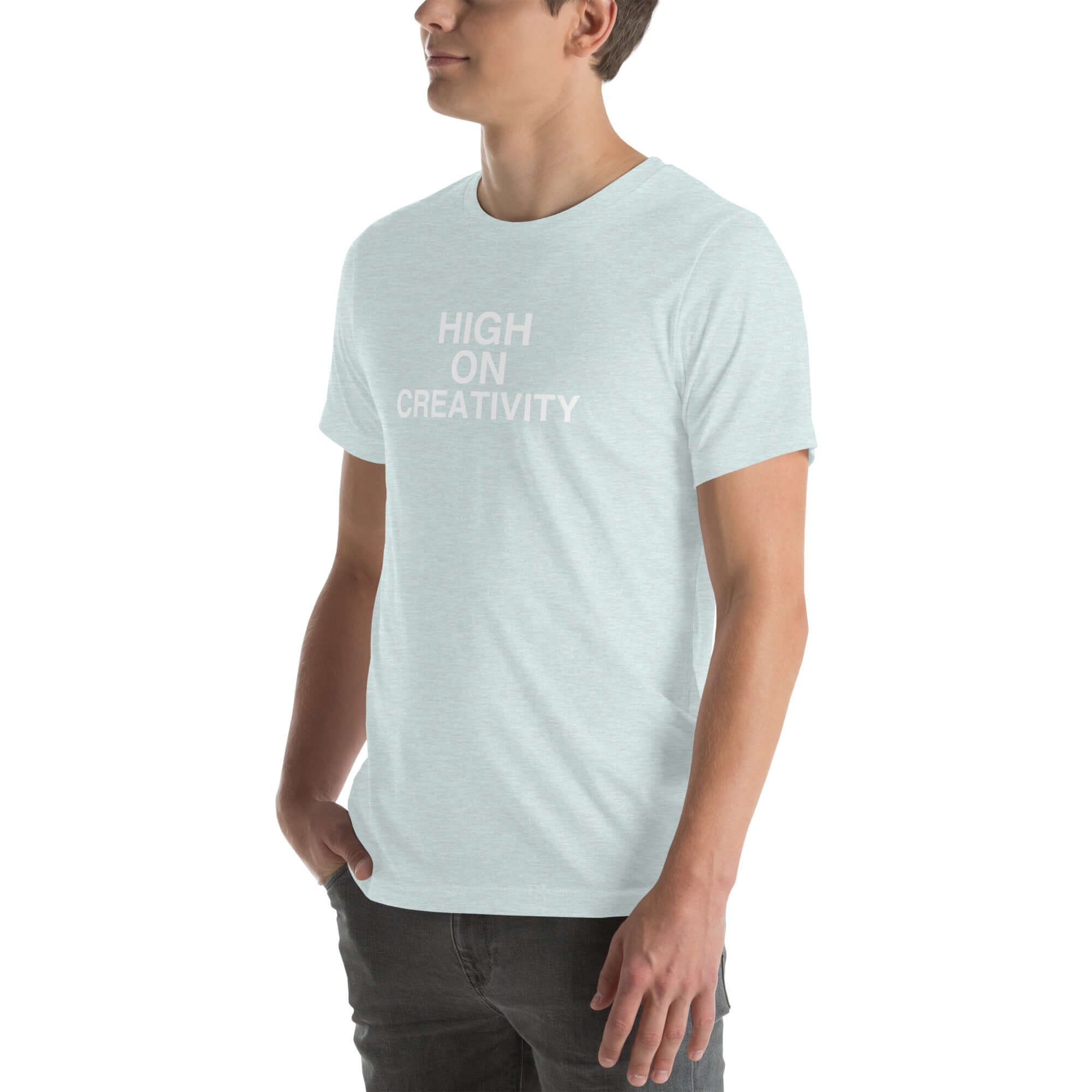 Man wearing a ice blue t-shirt with white text ‘HIGH ON CREATIVITY’, standing sideways with one hand in pocket