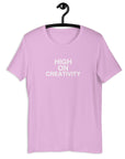 Lilac t-shirt on a hanger with the phrase “HIGH ON CREATIVITY” printed in white, centered on the chest.